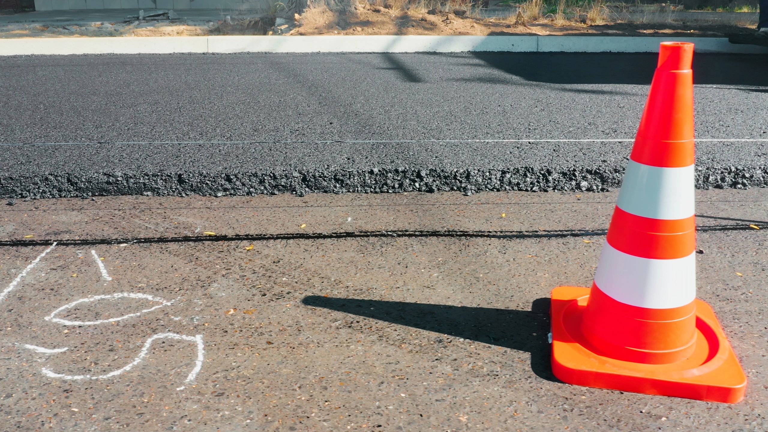 Traffic control cone and fresh asphalt at a road work site